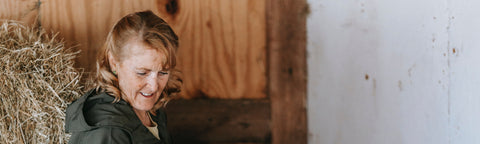 older woman lifting heavy bail of hay