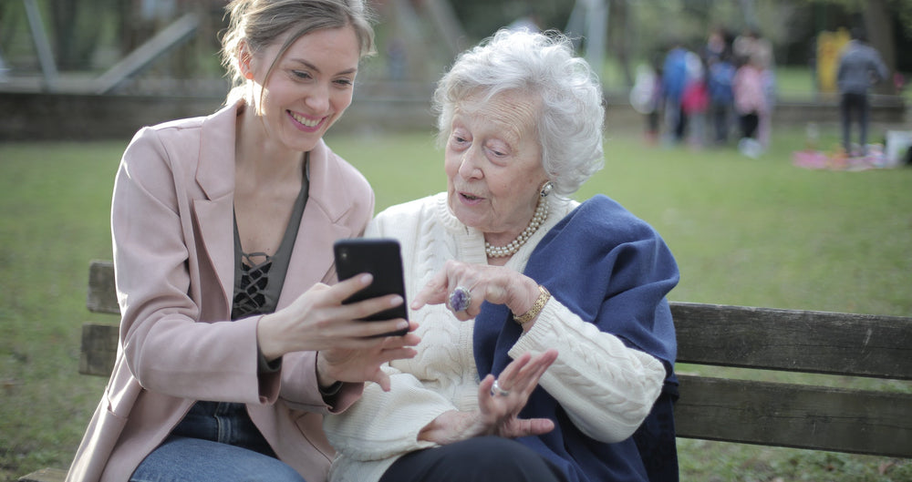 senior woman and young woman talking on park bench