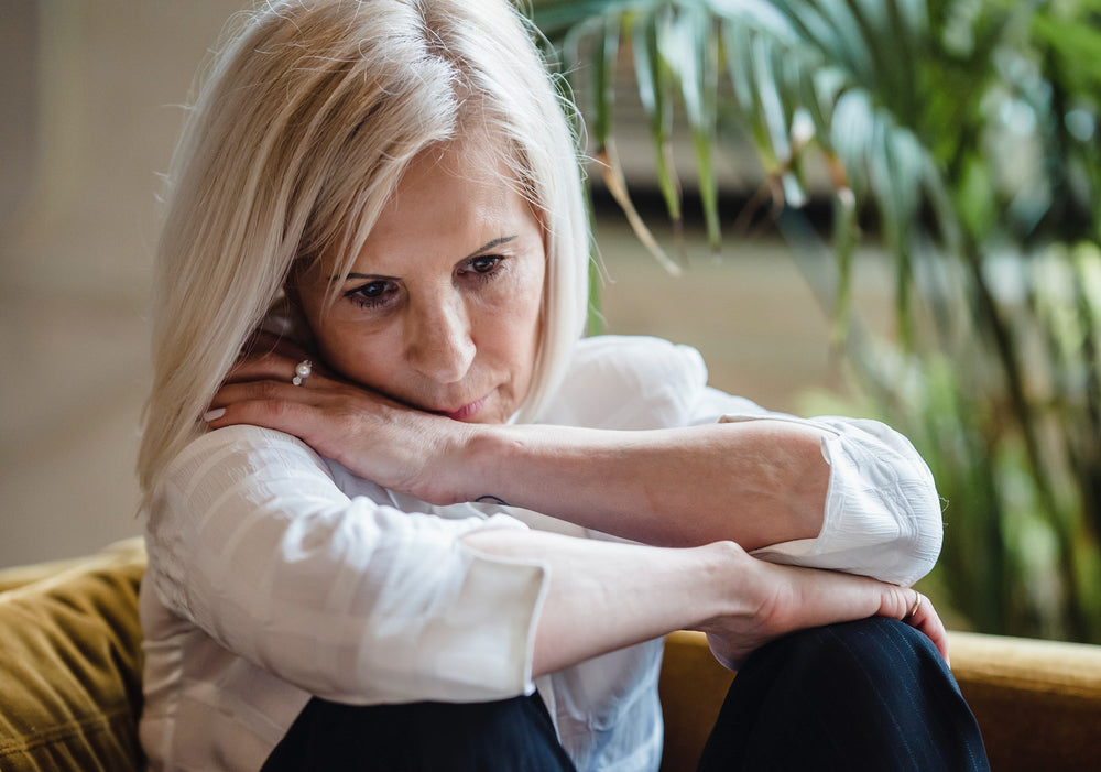 upset older woman sitting on couch