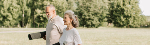 An Elderly Man and Woman Carrying Yoga Mats while Walking